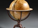 un vieux globe terrestre posé sur un socle, sur fond noir