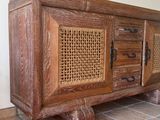 une armoire en bois avec une porte en rotin et des tiroirs