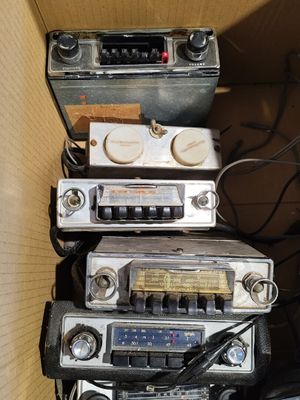 Plusieurs vieilles radios sont empilées les unes sur les autres dans une boîte en carton