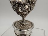 an image of a silver vase with a plant in it on a glass table