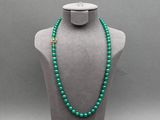 un collier de perles vertes sur un mannequin, muni d'un fermoir doré