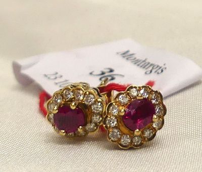 pair of ruby and diamond earrings on a white cloth with a red ribbon