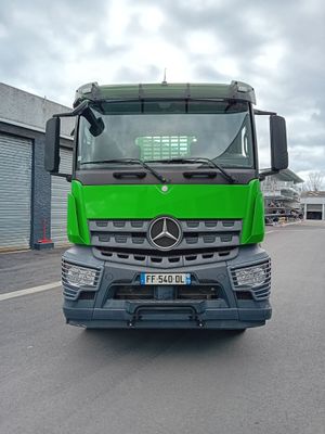 un camion vert qui roule dans la rue devant un immeuble
