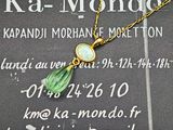une chaîne en or à laquelle est accroché un pendentif en verre vert