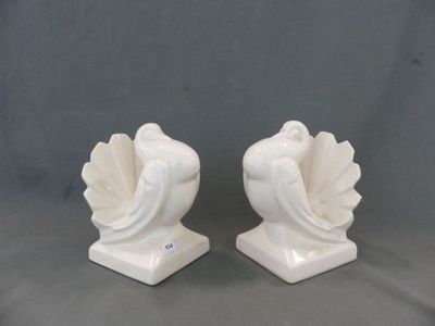deux figurines en céramique blanche représentant un oiseau, posées sur un socle