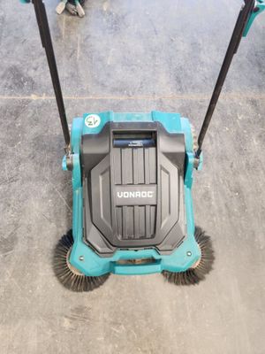 un gros plan d'un balai-brosse bleu et noir posé sur un sol en béton