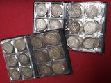 two boxes of silver coins sitting on top of a red surface