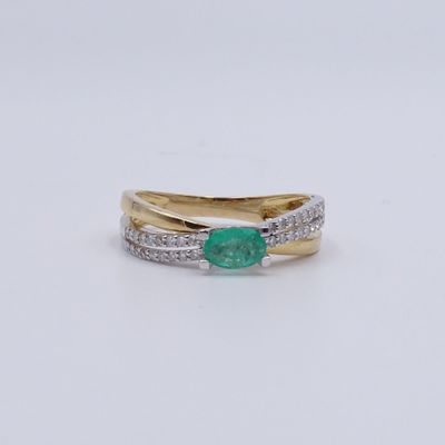 gros plan d'une bague avec une pierre verte et des diamants