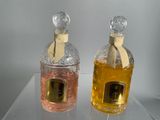 two bottles of perfume sitting on a glass shelf