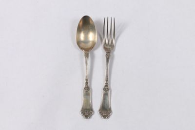deux cuillères et une fourchette en argent sur une surface blanche