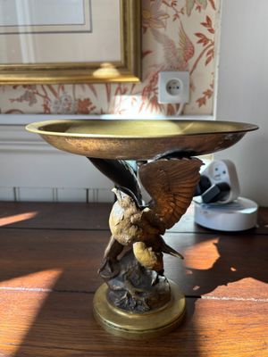 a bird that is sitting on top of a bowl on a table