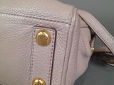 someone is holding a pink purse with gold buttons on it
