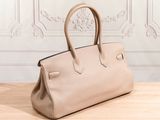 a beige leather handbag sitting on top of a wooden table