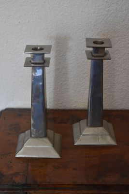 two metal candles that are on a wooden table