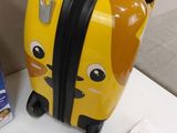 a yellow suitcase with a stuffed animal on top of it