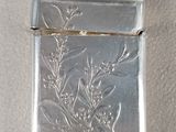 silver lighter with floral design on it sitting on a white surface