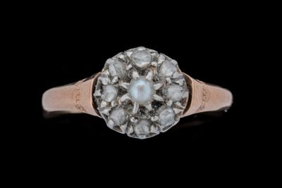 un gros plan d'une bague sertie d'un diamant et d'une perle sur fond noir