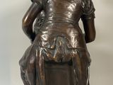 bronze statue of a man sitting on a box with his hands on his knees