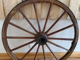 une grande roue en bois posée par terre près d'un mur