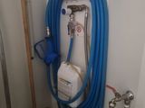 un tuyau bleu fixé au mur à côté des toilettes