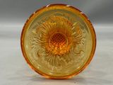 an orange glass plate with a flower design on it on a white surface