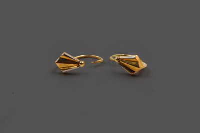 une paire de boucles d'oreilles en or posées sur une surface grise