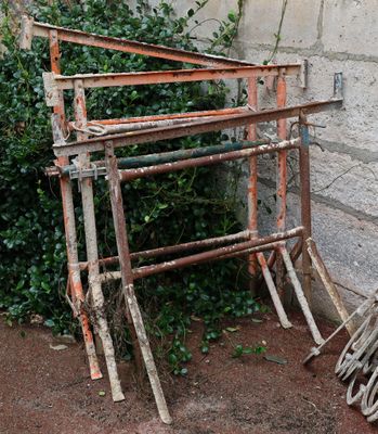 a pile of rusted wood leaning against a stone wall