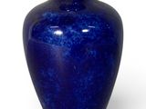 un vase bleu posé sur une surface blanche