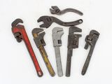 four wrenes and a pair of pliers on a white surface