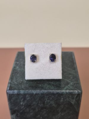 a pair of blue sapphire stud earrings sitting on top of a marble block