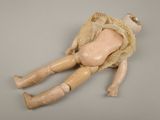 a wooden doll laying on the floor with a dress on