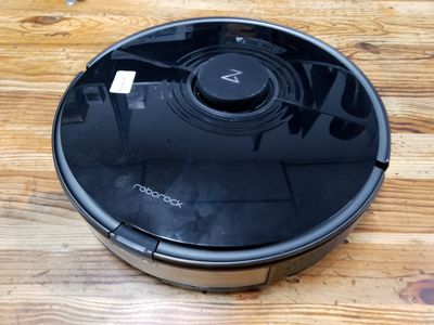 une photo d'un aspirateur robot posé sur une table en bois