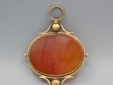 an image of a gold and red stone pendant on a white background