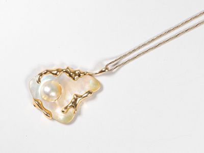 une image représentant un collier en or orné d'une perle blanche en forme de cœur
