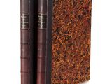 an old book with two leather bindings sitting on top of each other