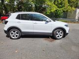 the white volkswagen suv is parked in a parking lot with trees in the background