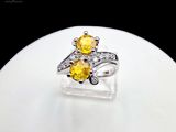 yellow sapphire and diamond ring on display on white surface