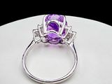 an image of a ring with a purple stone on top of a white surface