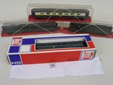 trois trains miniatures se trouvent dans une boîte posée sur une surface blanche