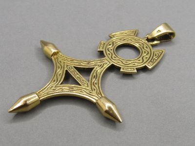a close up of a gold pendant with a cross on it