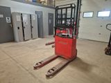 a red forklift in a warehouse with doors open