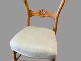 an old wooden chair with a blue upholstered seat on a gray background