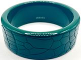 bracelet en plastique vert présentant une surface craquelée sur fond blanc