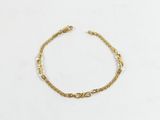 un bracelet en chaîne dorée orné d'un motif de nœud sur fond blanc