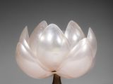 a white glass flower on a gold stand on a gray background
