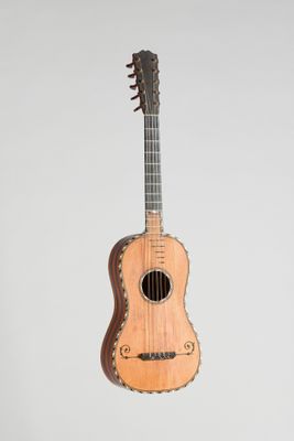 un gros plan d'une petite guitare en bois sur fond blanc