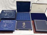 six cartons contenant des livres commémoratifs sont posés sur un lit recouvert d'un drap blanc