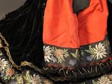 doll dressed in a black and orange dress with a black hat and red dress