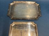 two silver trays with handles and handles on a blue background