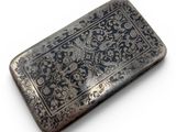 an antique silver cigarette case with a floral design on it